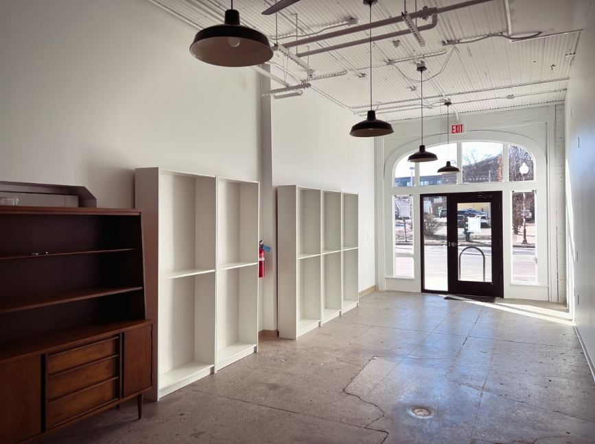 The interior of a bookstore being built out, empty bookshelves and other furniture lines the walls